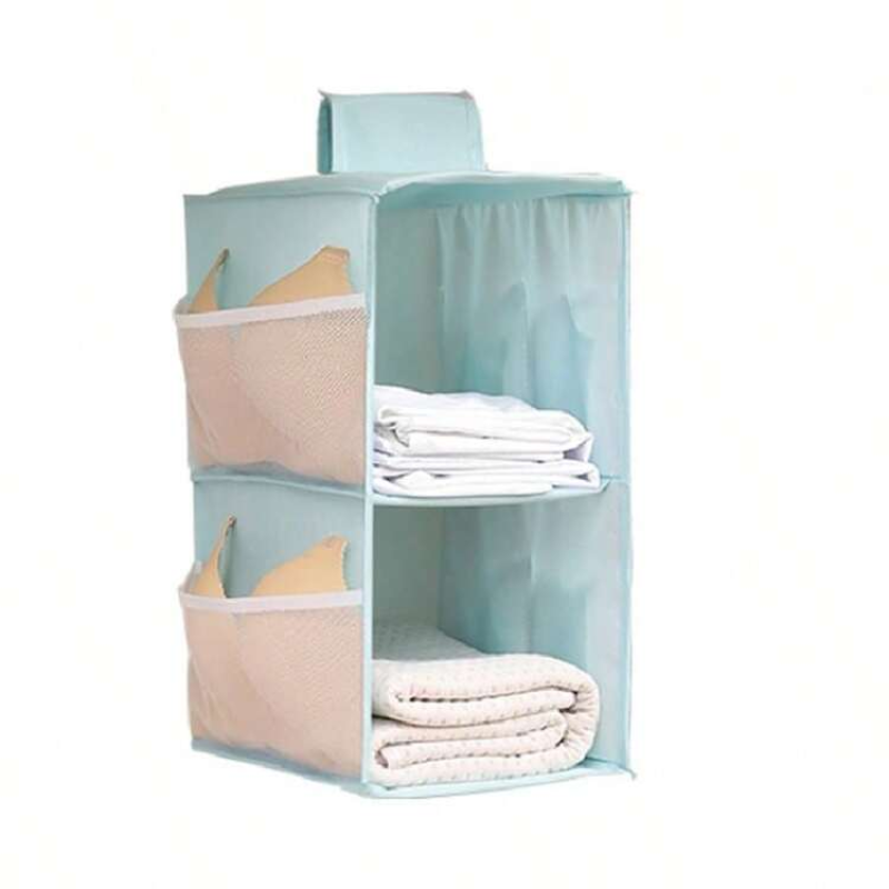 A light blue fabric hanging organizer with three tiers, shown holding folded white towels and a beige pillow. The organizer features mesh side pockets and a solid fabric back panel, set against a plain white background.