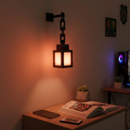 Wall-mounted lamp casting a warm glow on a table with books and a tablet.