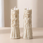 Two cream-colored LED taper candles shaped like skeleton bride and groom figures, standing side by side on a light beige surface against a soft neutral background.