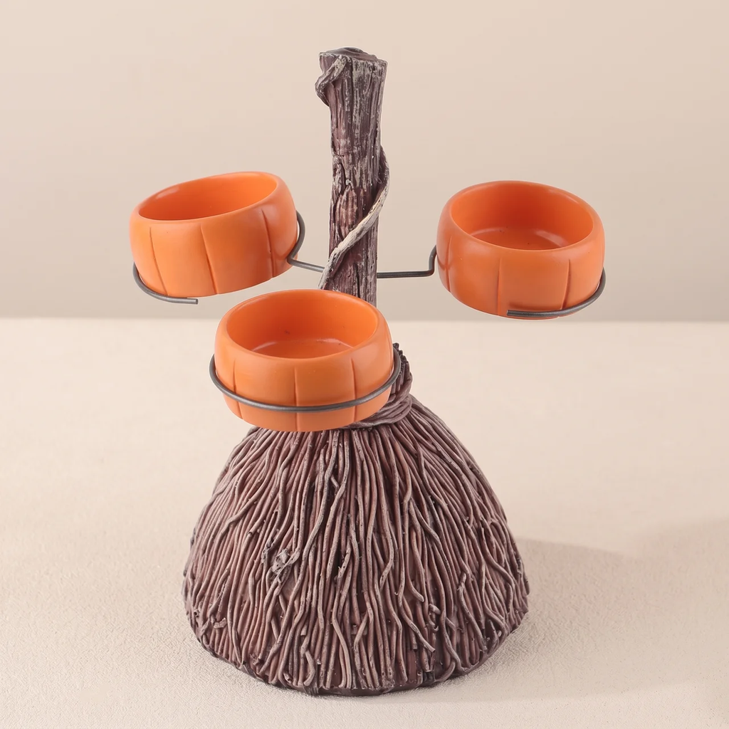 A decorative three-bowl pet feeder shaped like a tree trunk, with three orange bowls mounted on a faux wood branch structure, shown on a plain beige studio background.