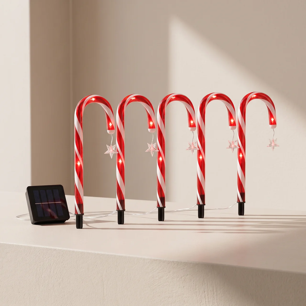 Six red and white striped candy cane holiday lights with built-in LED lights and small hanging white star ornaments, displayed on a beige surface next to a small solar panel.