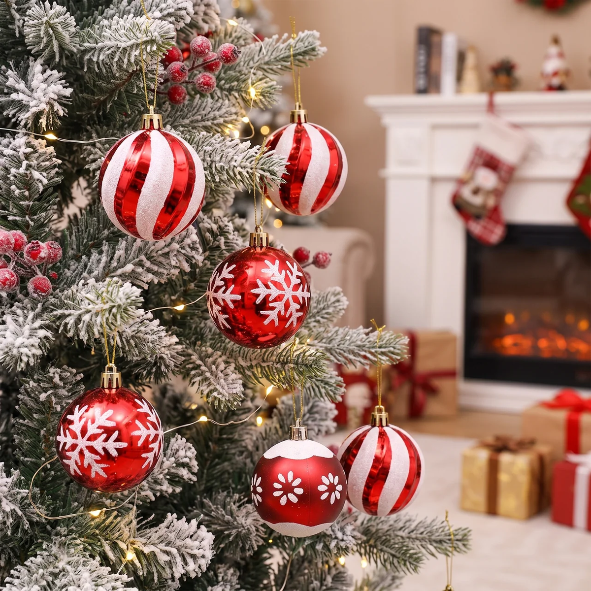 Red and white striped and snowflake Christmas tree ornaments hanging on a flocked Christmas tree in a cozy living room setting with a fireplace and stockings in the background.