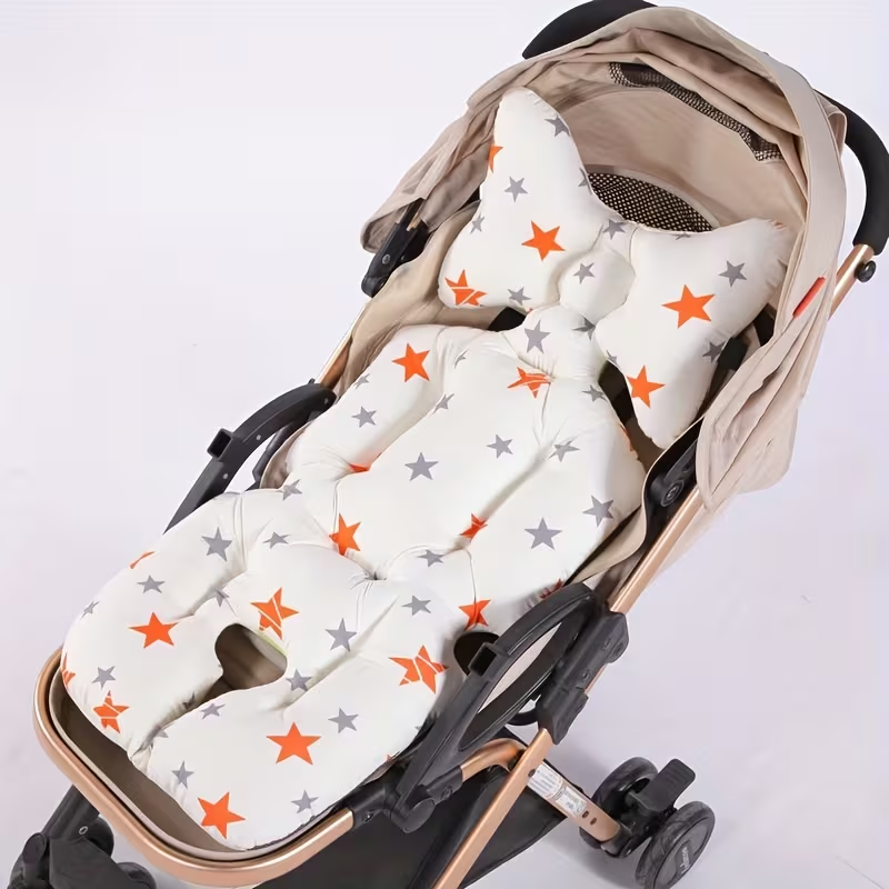 A padded baby stroller cushion set with a matching footmuff, featuring an off-white background with a pattern of orange and gray stars, shown installed inside a stroller.