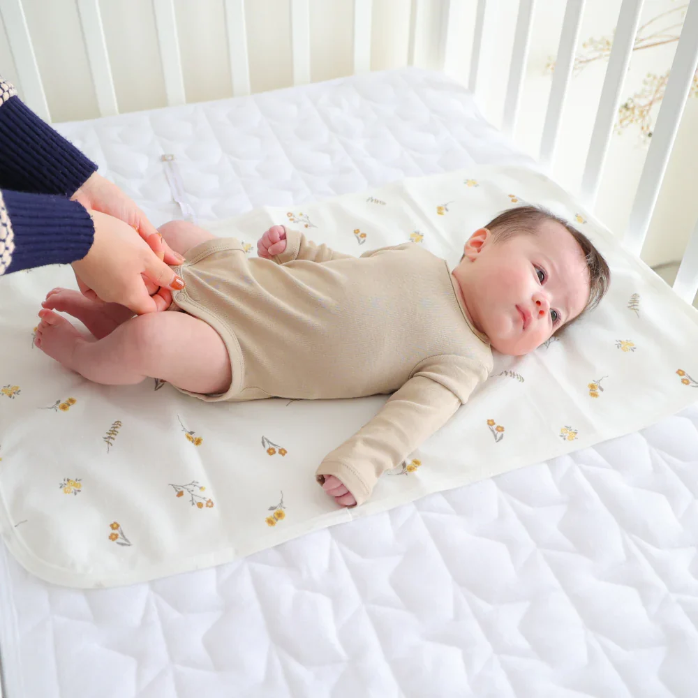 Baby lying on a white crib mattress with a floral pattern
