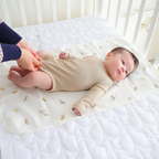 Baby lying on a white crib mattress with a floral pattern