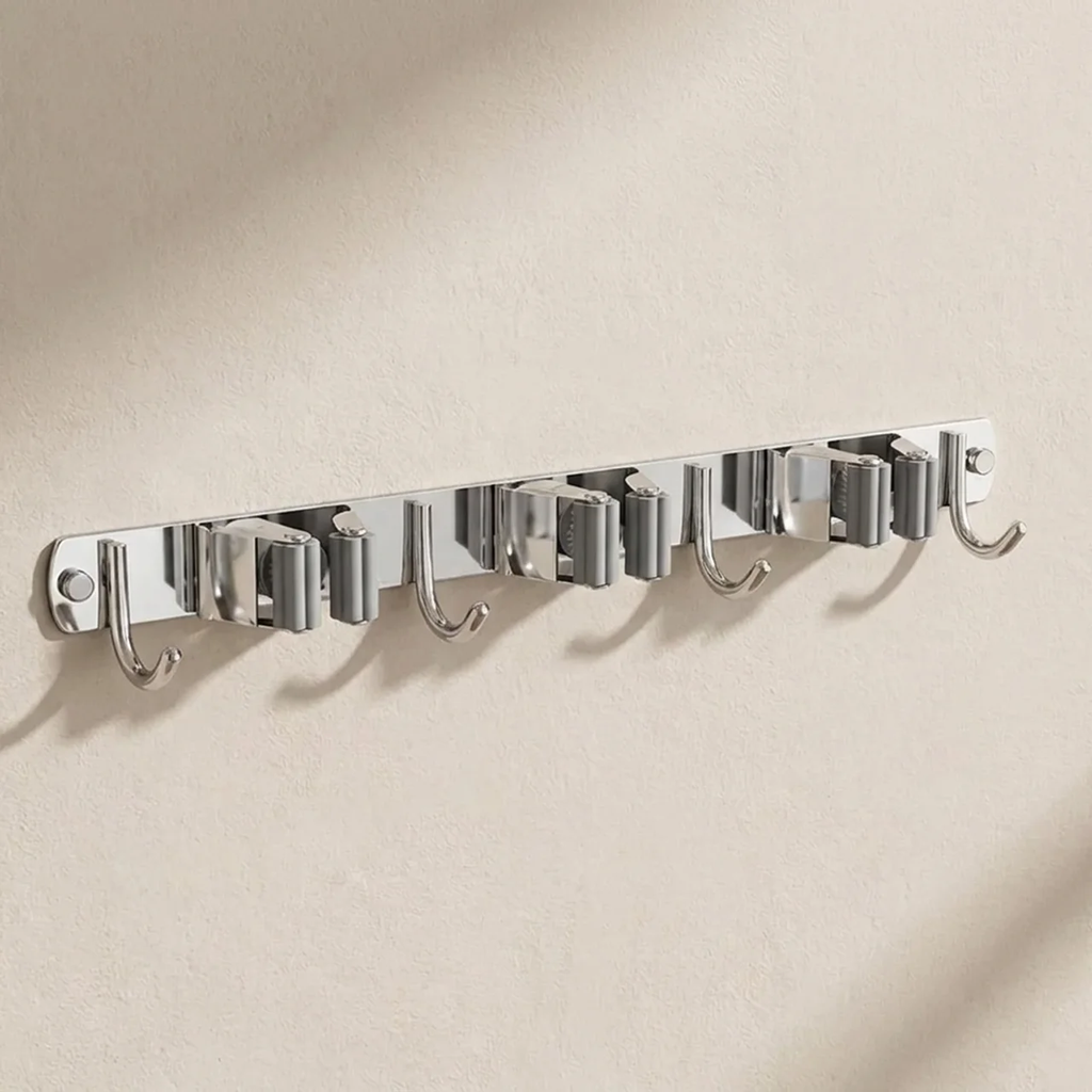A wall-mounted silver metal hook rack with six hooks, shown mounted on a textured beige wall with soft shadows.