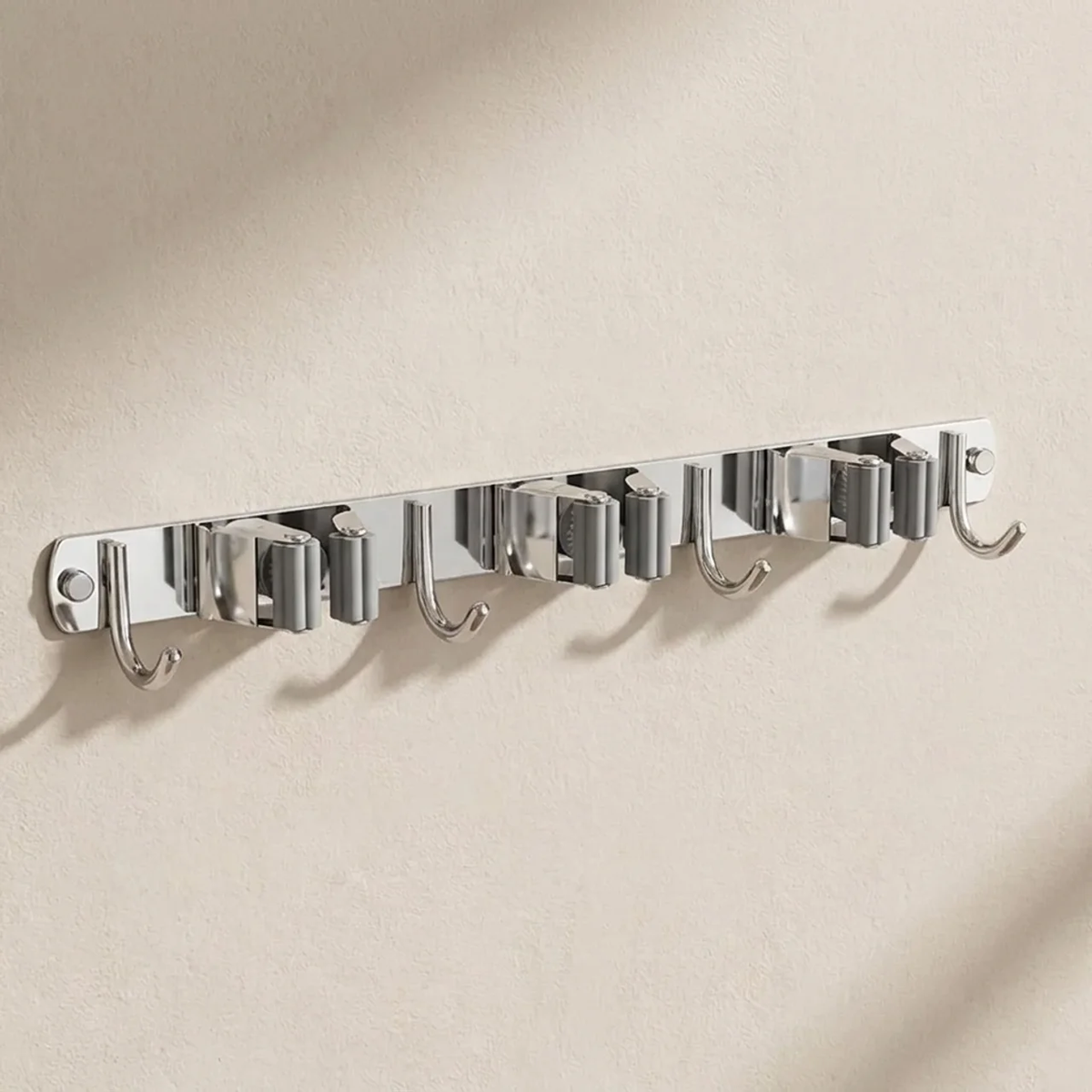 A wall-mounted silver metal hook rack with six hooks, shown mounted on a textured beige wall with soft shadows.