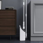 White vacuum cleaner against a gray wall with wooden furniture.