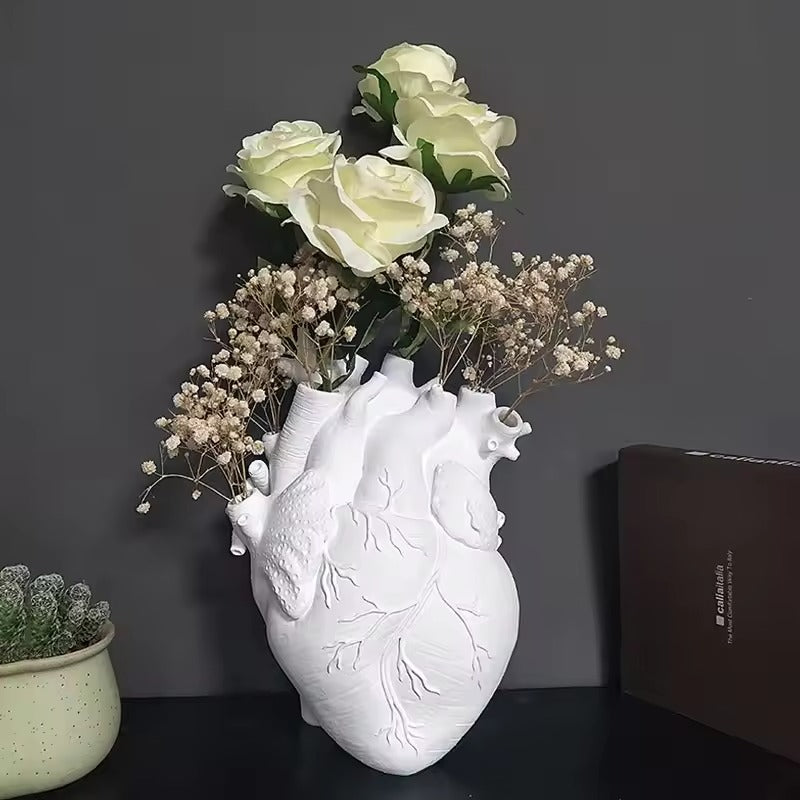 Heart-shaped vase with flowers on a dark surface