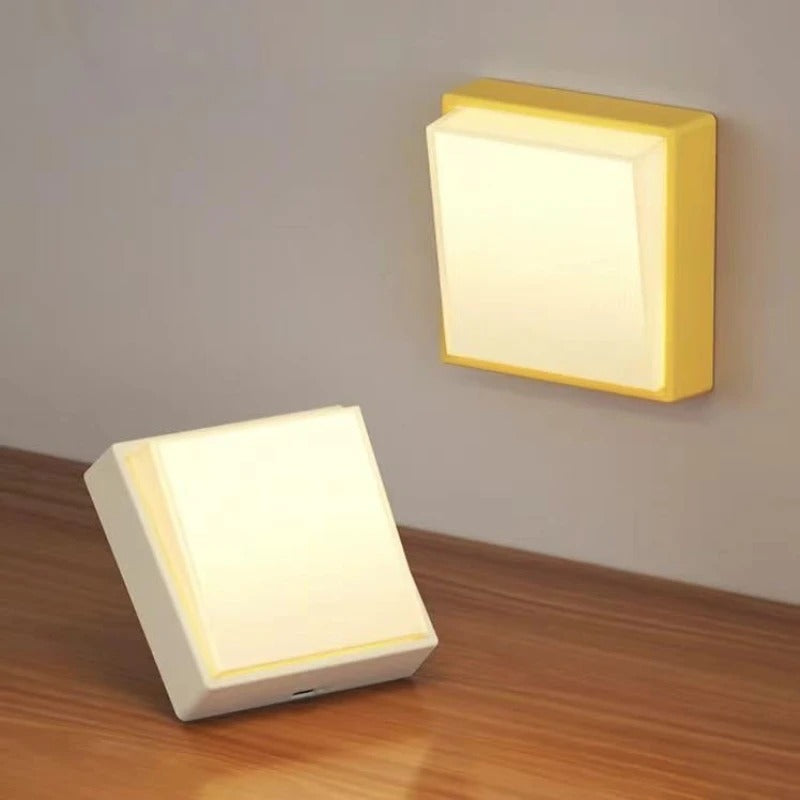 Two square wall lights, one on a wooden surface and one mounted on a wall.