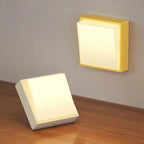 Two square wall lights, one on a wooden surface and one mounted on a wall.