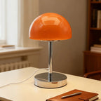 Orange table lamp on a desk with a notebook and pen in a home setting