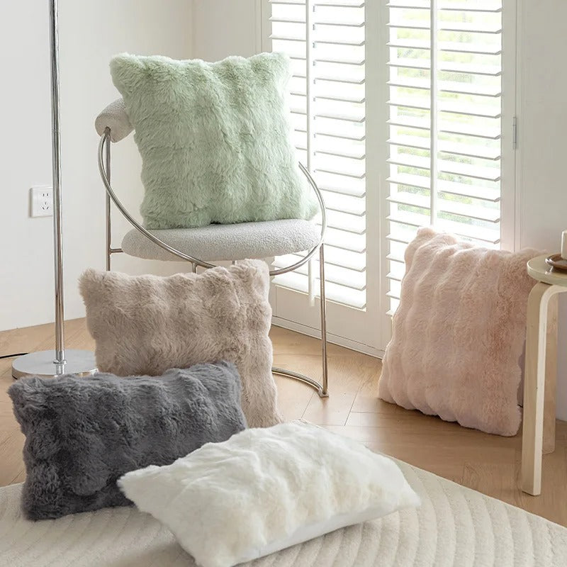 Furry cushions in various colors on a chair and bed in a bright room.