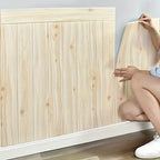 Person assembling a wooden headboard against a light blue wall.