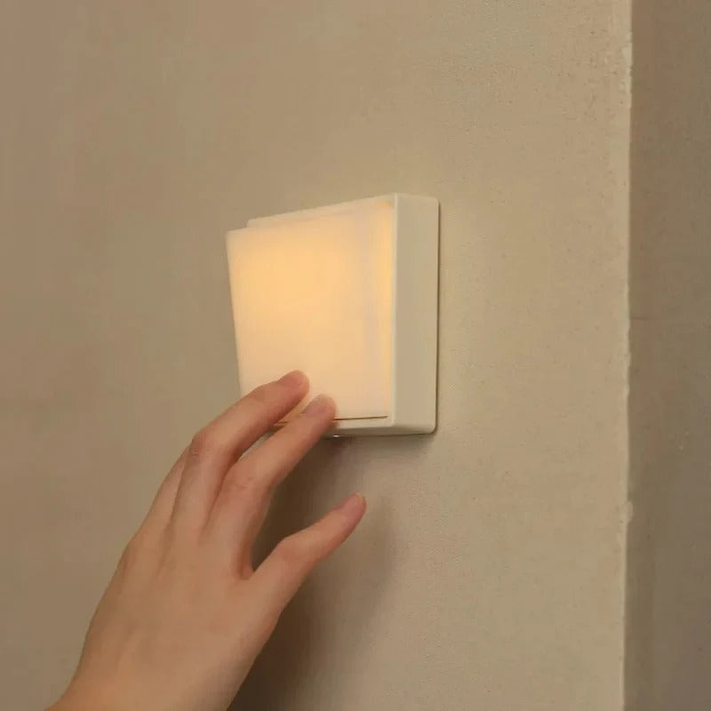 Hand turning on a wall-mounted light fixture.