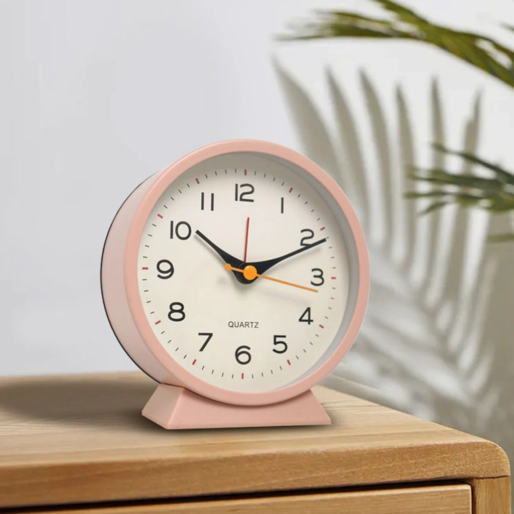 Pink alarm clock on a wooden surface with a light gray background