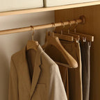Brown coat and pants hanging on wooden hangers in a closet.