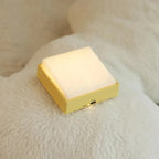 Square night light with a yellow base and white top on a soft surface