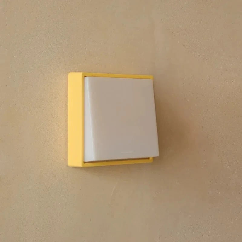 Light switch with yellow frame on a beige wall