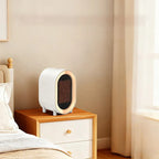 Small white and gold space heater on a wooden nightstand next to a bed.