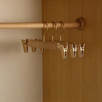 A wooden closet rod organizer with metal hangers and clips mounted on a wooden wardrobe door and rod, shown in a real interior setting.