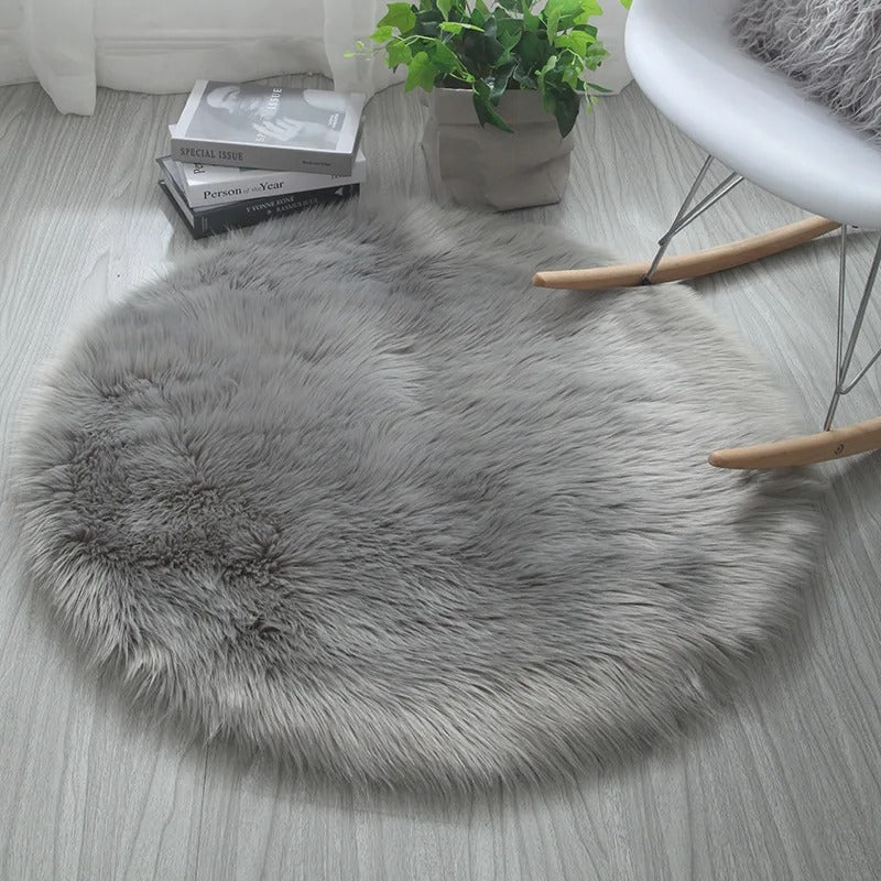 Fluffy gray rug on a wooden floor with a plant and books in the background.