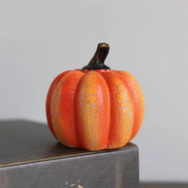 Small cracked orange pumpkin on a gray surface with a light gray background
