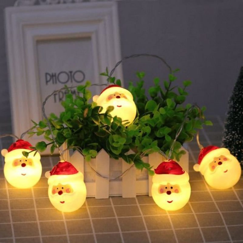 String lights shaped like Santa Claus with a plant and photo frame in the background.