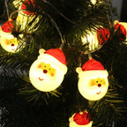 String lights shaped like Santa Claus heads on a Christmas tree.