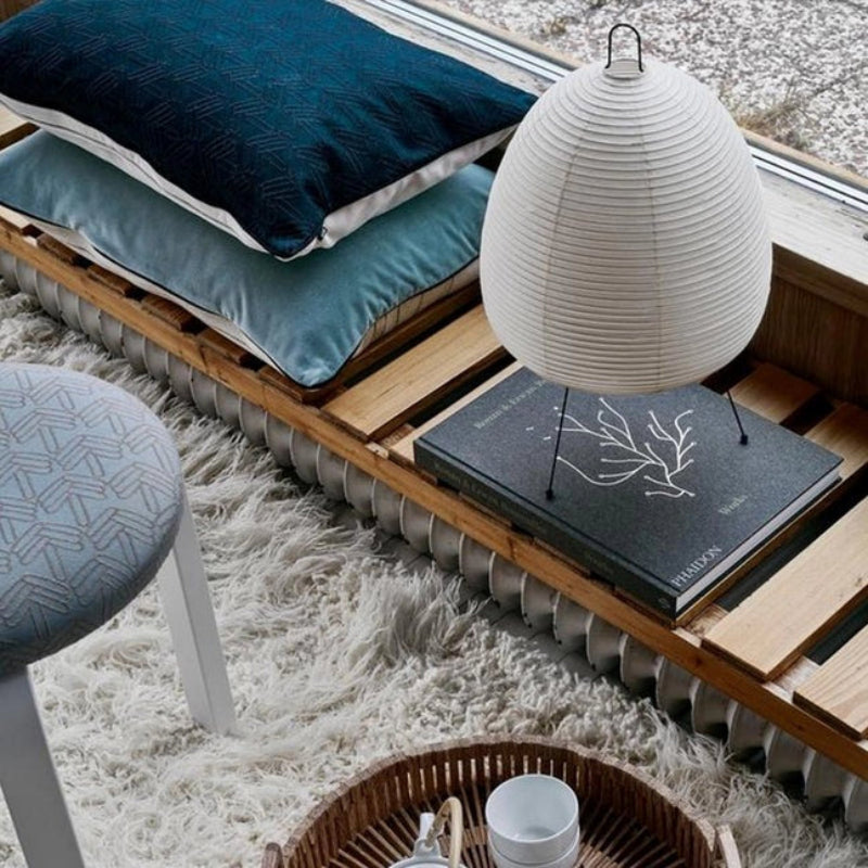 Pallet with pillows, a lamp, and books on a textured surface
