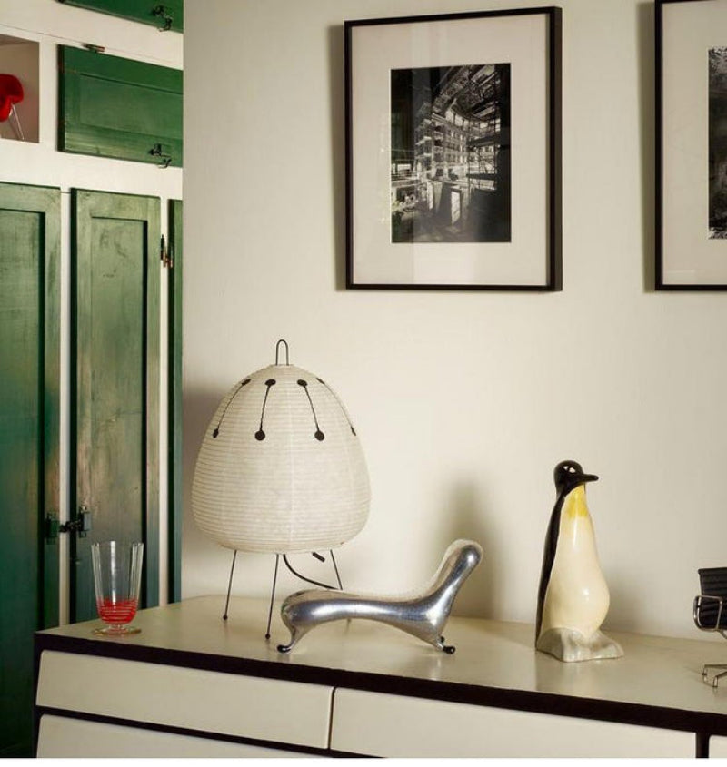 Decorative items on a shelf including a lamp, chair, and penguin figure with framed pictures on the wall.