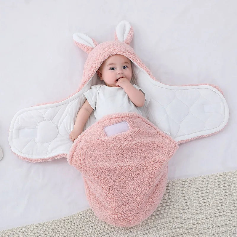 Baby wrapped in a pink bunny-themed swaddle on a light gray background