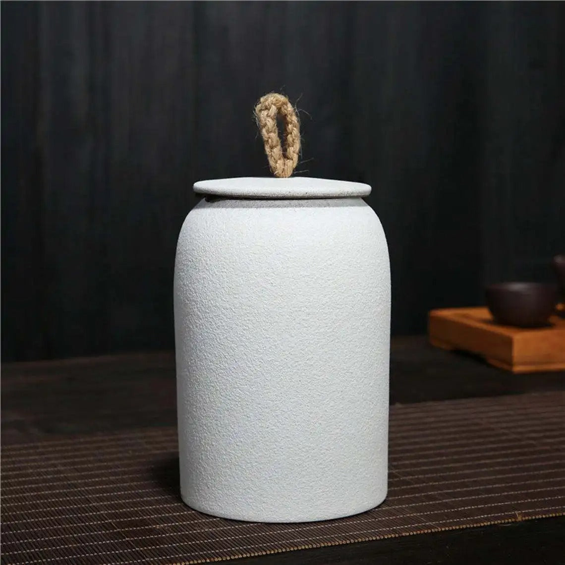 White textured ceramic jar with a lid on a dark surface
