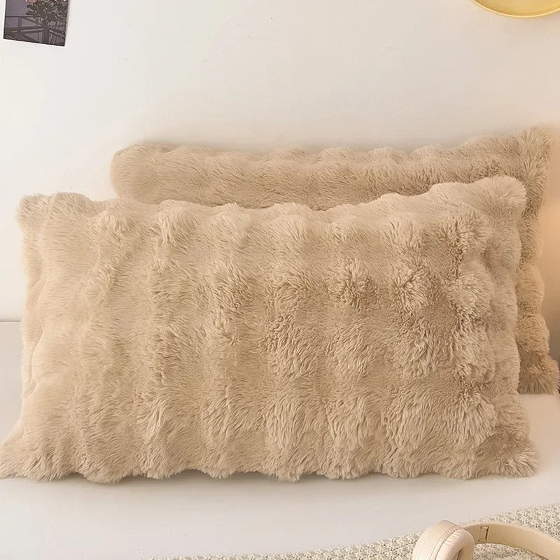 Beige fluffy pillows on a white surface with a neutral background