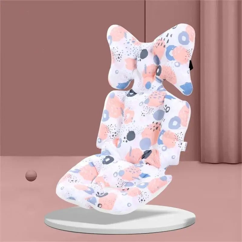 A baby car seat cushion cover with a white background and a colorful abstract pattern of pink, blue, and gray shapes, shown floating on a white circular base against a dusty pink background.