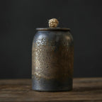 Rustic metal canister with a lid on a wooden surface against a dark background
