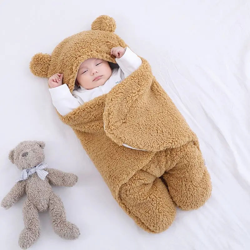 Baby sleeping in a brown teddy bear outfit with a small teddy bear on a white background