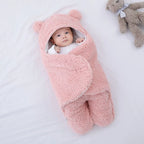 Baby wrapped in a pink fluffy blanket with bear ears on a white background
